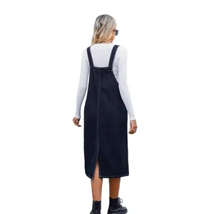 Back view of a navy blue denim overall midi dress with a split hem on white background.