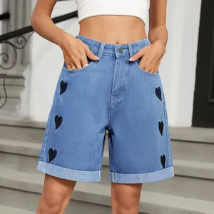 Détail d'un short en jean bleu taille haute avec imprimé cœurs noirs et revers