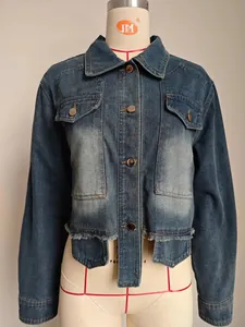 Detail shot of blue washed cropped denim jacket featuring raw hem and chest pockets.
