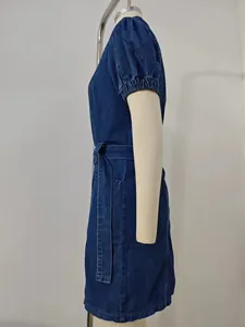 Side view of a dark blue denim dress with puff sleeves and waist belt detail
