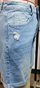 Détail d'un trou déchiré et d'un ourlet retroussé sur un short en jean bleu clair