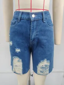Detailed view of heavy distressing and raw hem on blue denim shorts for women's casual wear