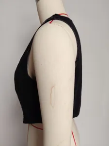 Close-up side view of washed black vest on mannequin showing tailored waist construction.