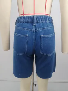 Detail view of women's retro mid-rise denim bermuda shorts with raw hem and pockets.