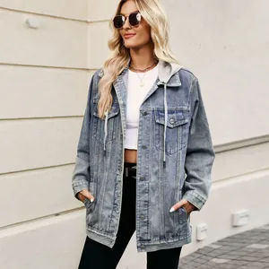 Blonde vrouw buiten die een losse lichtblauwe spijkerjas met capuchon draagt.
