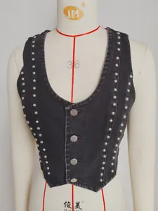 Close-up detail of a black vintage denim vest with silver studs and metal buttons
