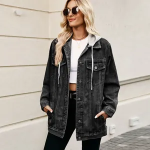 Oversized zwart denim jack met grijze capuchon gedragen door een model in de buitenlucht