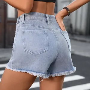 Detailed macro view of washed denim shorts featuring raw hem and beaded side accents