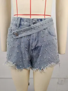 Close-up detail of light blue denim shorts featuring rhinestone beads and frayed hem.