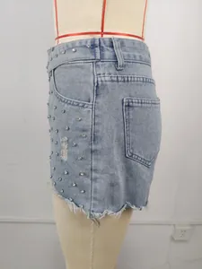 Side view of washed denim shorts featuring heavy beadwork and distressed frayed hem.