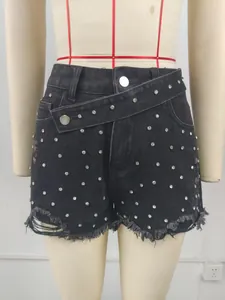 Detailed view of women's washed black denim shorts with rhinestone studs and frayed hem.