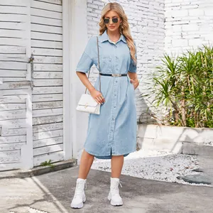 Full-body shot of a light blue denim shirt dress styled with a white bag and boots.