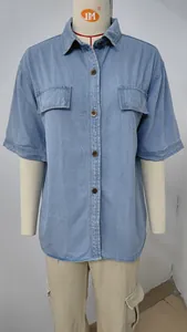 Dettaglio frontale di una camicia a maniche corte in denim azzurro con tasche e bottoni