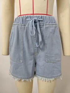 Close-up detail of light blue high waisted denim shorts with raw hem and drawstring.