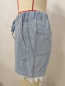 Side view detail of light blue high waist denim shorts with frayed hem and elastic drawstring