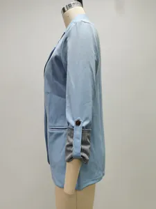 Dettaglio laterale di blazer azzurro con polsini a righe