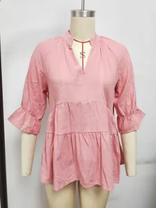 Dettaglio camicetta rosa con scollo a V, balze a strati e maniche a campana arricciate.