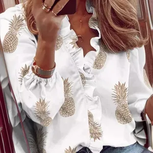 White long-sleeved blouse for women featuring golden pineapple print and ruffle trim