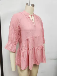 Dettaglio ravvicinato degli strati a pieghe su una camicetta estiva rosa con scollo a V