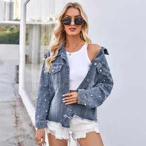 Detailansicht der gewaschenen blauen Jeansjacke mit Perlenverzierung und ungesäumtem Rand.