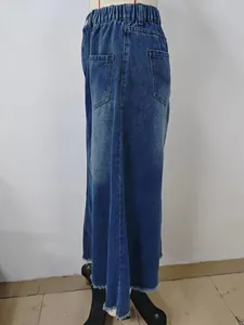 Side view of washed blue denim midi skirt with frayed hem and elastic waist
