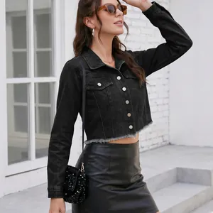 Dettaglio di una giacca di jeans corta nera con orlo a vivo alla moda e bottoni metallici.