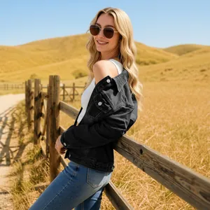 Back view of model wearing black denim jacket with metal buttons in a countryside setting
