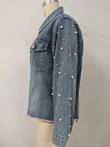 Detailaufnahme eines blau gewaschenen Jeansjackenärmels mit eleganten Perlenverzierungen