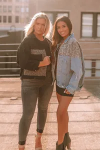 Outdoor lifestyle shot of two women wearing leopard print patchwork denim jackets
