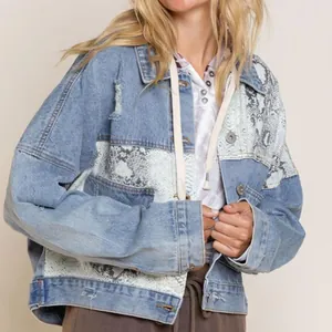 Detail view of oversized distressed denim jacket with grey snake-skin patchwork design.