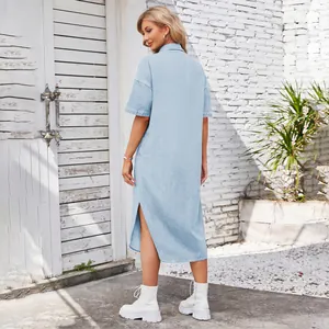 Rear view of model wearing a light blue washed denim maxi dress with side slit