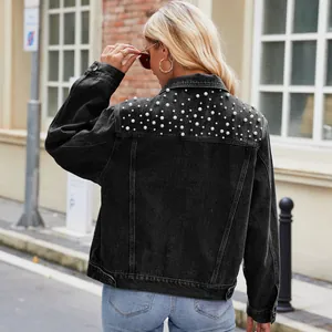 Close-up view of elegant pearl embellishments on the back yoke of a black denim jacket
