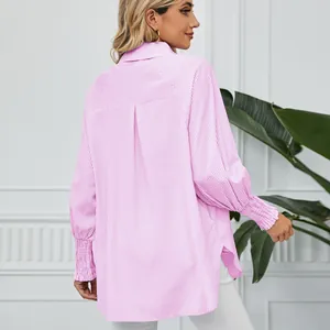 Vue arrière d'un chemisier rayé rose oversize avec des détails de poignets smockés élégants.