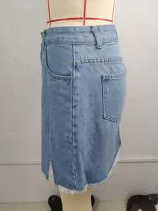 Detail view of a washed blue denim mini skirt featuring a side slit and frayed hem.