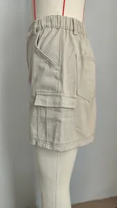 Détail latéral d'une jupe cargo en jean kaki avec taille élastique et poches cargo