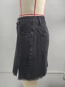 Side detail of a washed black denim mini skirt featuring a slit and frayed hem.