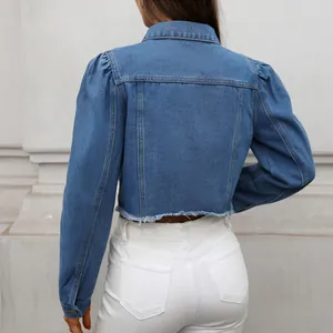 Back view of stylish washed blue cropped denim jacket with puff sleeves and raw hem.
