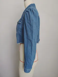 Side profile of a washed blue cropped denim jacket featuring puff sleeves and frayed hem