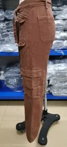 Side profile of brown washed denim cargo pants featuring multiple utility pockets on mannequin