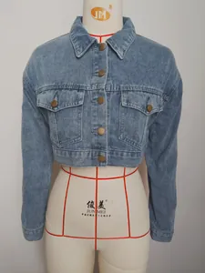 Macro view of a vintage light wash cropped denim jacket featuring metallic buttons.