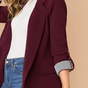 Dettaglio ravvicinato del blazer bordeaux con maniche a righe risvoltate e bottone