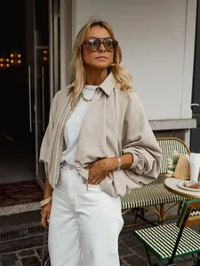 Detailed shot of a stylish loose batwing sleeve beige jacket paired with white trousers