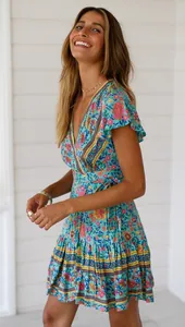 Nahaufnahme eines blauen Boho-Mini-Blumenkleids mit V-Ausschnitt an einem lächelnden Modell