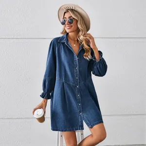 Woman wearing loose dark blue washed denim long-sleeve mini dress with button front