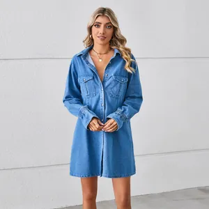 Loose light wash denim shirt dress with long sleeves and chest pockets on white background