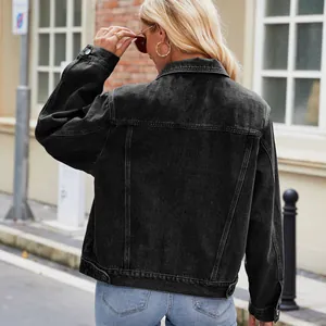 Back view of a women's slim fit washed black denim jacket in a street setting.
