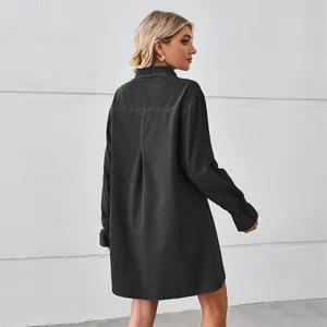 Back view of a loose black washed denim shirt dress featuring a stylish pleat detail.