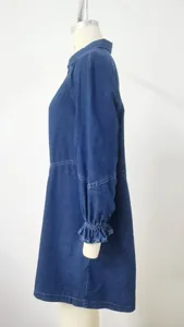 Side profile detail of a loose dark blue washed denim dress with ruffled cuffs