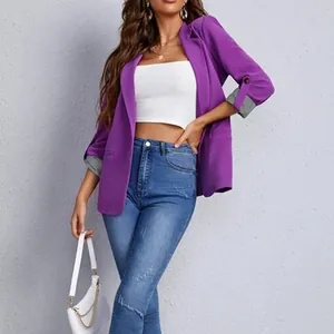 Dettaglio di un elegante blazer viola aperto con maniche risvoltate indossato dal modello