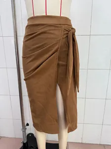Macro detail of elegant brown faux suede skirt featuring a side tie knot and front slit